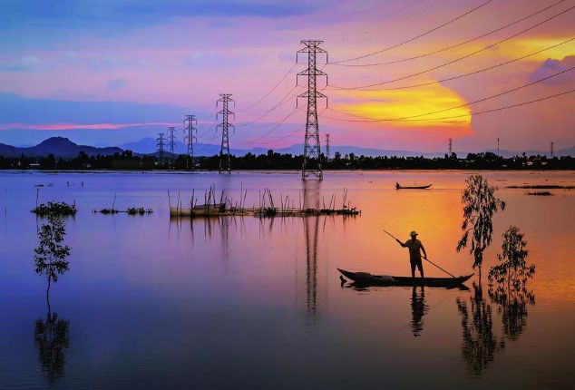 Hombre en canoa de pie sobre el agua durante el atardecer, simbolizando la tranquilidad y la ciberseguridad en infraestructuras críticas.